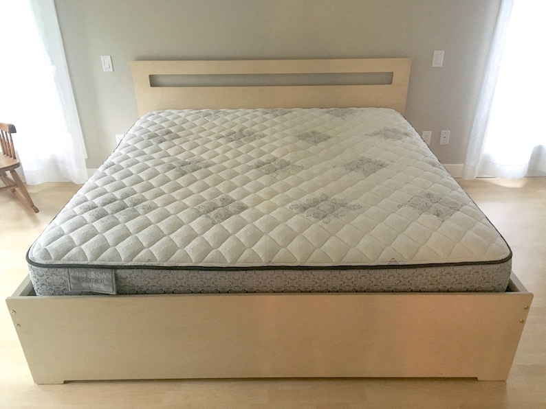 May include: A light wood platform bed frame with a white mattress and a headboard with a rectangular cutout.