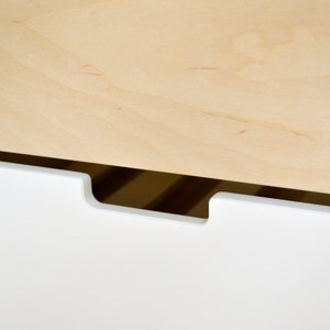 May include: A white drawer with a cutout handle. The drawer is made of wood and has a light wood top.