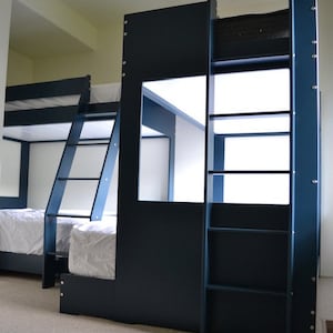 May include: A dark blue bunk bed with a ladder and shelves. The bed has a white mattress and a white sheet. The bed is made of wood and has a modern design.