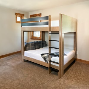 May include: A wooden bunk bed with a black ladder and a black top rail. The bed has a white mattress and a black and white plaid blanket on the bottom bunk.