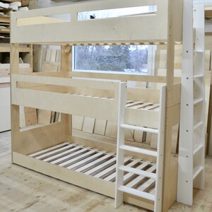 May include: A wooden bunk bed with a white ladder. The bed is made of natural wood and has a simple design. The ladder is attached to the side of the bed and has five steps.