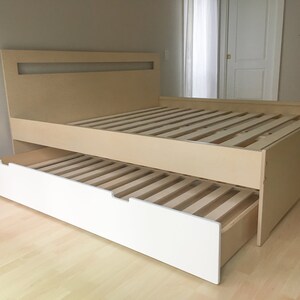May include: A light wood platform bed frame with a white under-bed drawer. The drawer is pulled out, revealing the slatted base of the bed.