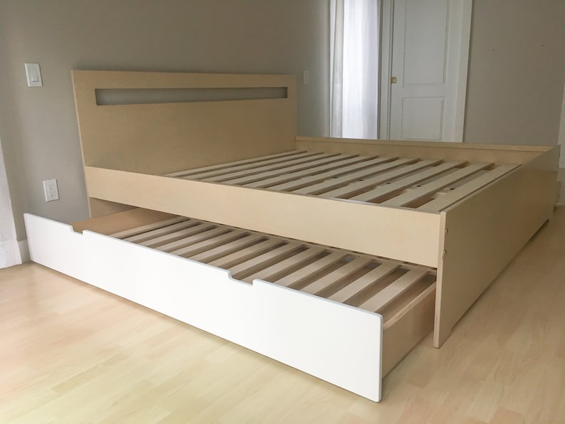 May include: A light wood platform bed frame with a white under-bed drawer. The drawer is pulled out, revealing the slatted base of the bed.