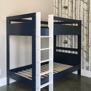 May include: A navy blue bunk bed with a white ladder. The bed has a slatted mattress support and is made of wood.