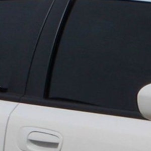 May include: White car with a tinted window displaying a white "NIRVANA" decal. The decal is in a bold, sans-serif font. The car's side mirror is visible.