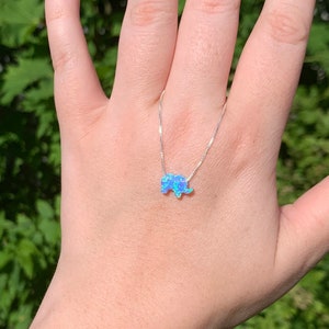 May include: A silver chain necklace with a blue opal elephant pendant.