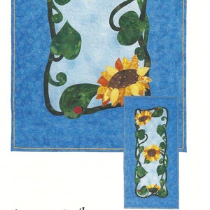 May include: A quilting pattern featuring a vine with sunflowers and leaves on a blue background. The pattern is titled "Summer Smiles #0374" and is from "a little more effect pattern company".