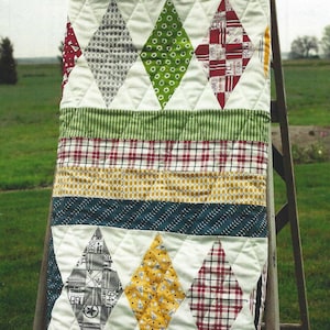 May include: A quilt pattern called "prep" from the "VARSITY" fabric collection. The quilt is made with a variety of colorful fabrics, including red, green, yellow, and blue. The quilt is 63 inches by 63 inches.