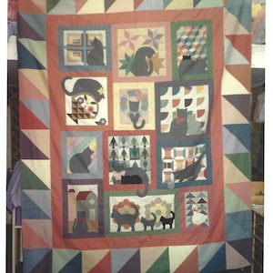 Puede incluir: Una colcha de patchwork con una cuadrícula central de doce bloques cuadrados, cada uno con varias siluetas de gatos negros, motivos florales y un pato. La colcha está enmarcada por un borde ancho de triángulos multicolores en patrón de sierra.