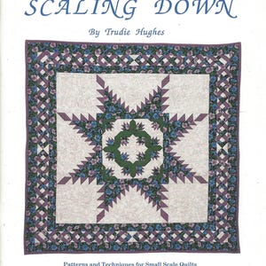 May include: A book cover titled SCALING DOWN by Trudie Hughes, featuring a square quilt with a central green and floral star pattern, surrounded by a white floral background and a purple and blue floral border with a woven lattice design.