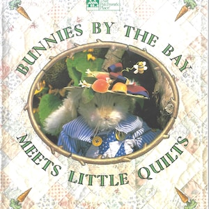 Puede incluir: Una portada de libro titulada Bunnies by the Bay Meets Little Quilts con un conejo de peluche blanco que lleva un sombrero de paja con frutas y una camisa de rayas azules sobre un fondo de patchwork claro con ilustraciones de zanahorias.