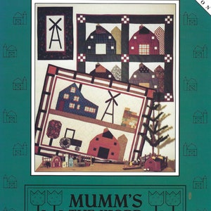 Op de afbeelding: Een quiltpatroon met een landelijk tafereel met huizen, een windmolen en een tractor. Het patroon is getiteld "A Country Mile" en is afkomstig uit de "Vintage Village Collection" van "Mumm's The Word".