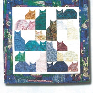 May include: A patchwork quilt with a repeating pattern of cat silhouettes in various fabrics. The quilt has a white central panel with cat shapes in shades of blue, green, pink, and gold. The border is a mix of blue and green patterned fabric. The text "Cat Nap" is at the top.
