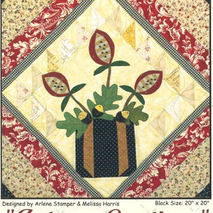 May include: A quilted square featuring a floral design with the text "Autumn Greetings." The central image is a vase with flowers and leaves. The quilt measures 20 x 20 inches. The pattern is "Forever Flowers, Pattern 5 of 7."