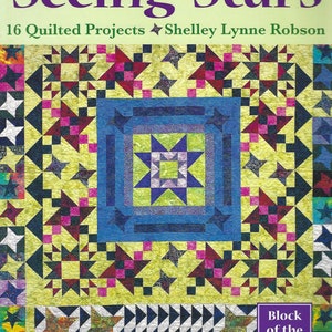 Puede incluir: Una portada de libro con un patrón de colcha colorido con estrellas. El título es "Seeing Stars" y el subtítulo es "16 Quilted Projects Shelley Lynne Robson". El libro es parte de una serie "Block of the Month".