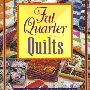 Puede incluir: Un libro titulado "Fat Quarter Quilts" de M'Liss Rae Hawley. La portada presenta un diseño de colcha de retazos colorido con un fondo amarillo y un título en morado y rojo. El libro está rodeado de pilas de cuadrados de tela.
