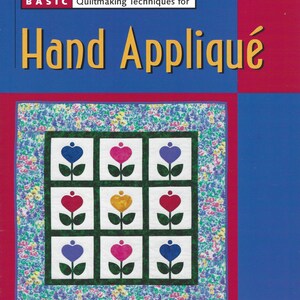 May include: A softcover instructional book titled Your First Quilt Book Basic Quiltmaking Techniques for Hand Appliqué by Mimi Dietrich. The cover features a quilt design with nine white squares containing colorful heart and flower motifs.