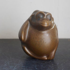 May include: A brown ceramic figurine of a bird with a round body and a small beak. The bird has a speckled brown glaze.