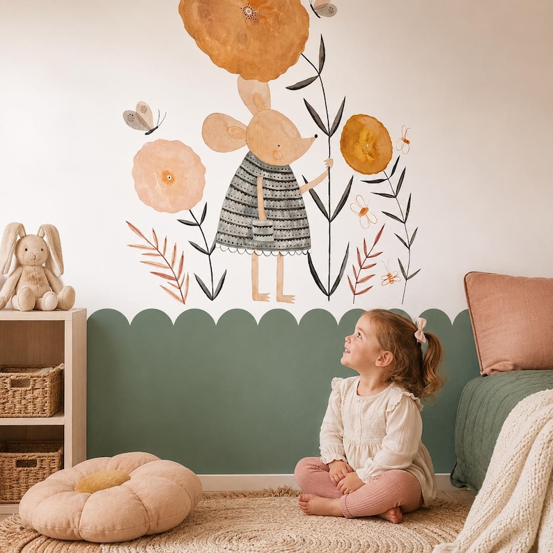 May include: A wall decal featuring a watercolour illustration of a mouse wearing a grey striped dress, surrounded by large orange flowers, thin black stems, and small butterflies. The design is applied to a white wall above a sage green scalloped border.
