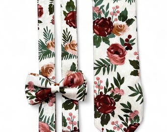 Puede incluir: Un conjunto de accesorios florales, que incluye tirantes, una pajarita y una corbata. Los artículos presentan un fondo blanco con un patrón de elementos florales burdeos, melocotón y verdes. Los tirantes tienen clips metálicos marrones.