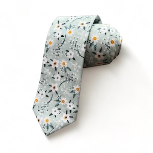 May include: A light green necktie with a white and yellow floral pattern.