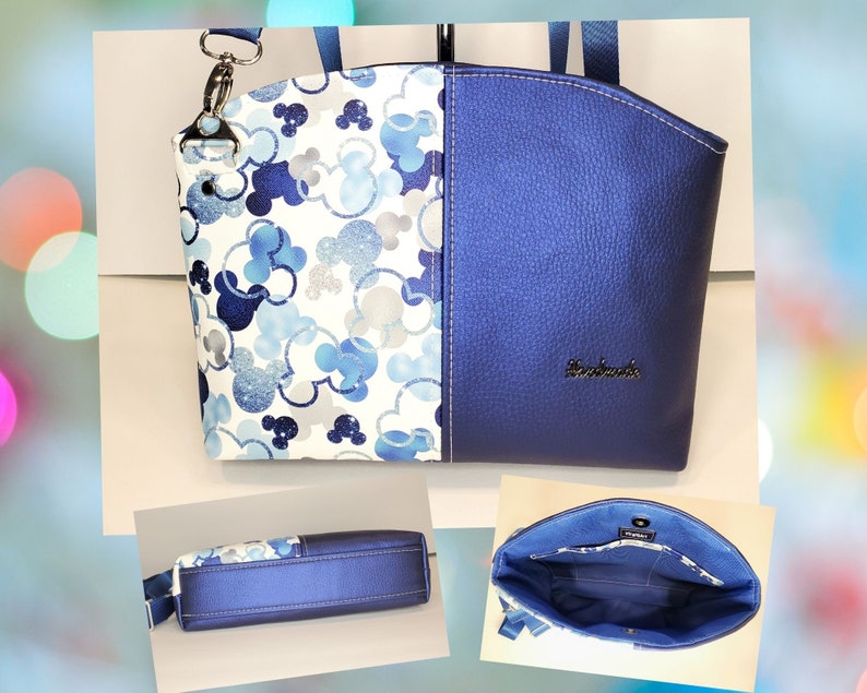 May include: A blue and white tote bag with a Mickey Mouse print on one side and a solid blue side. The bag has a top zipper closure and a detachable shoulder strap. The bag is handmade and has the word "remarkable" embossed on the blue side.