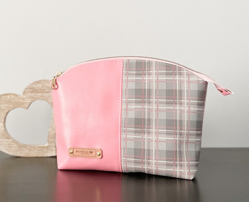 May include: Pink and gray plaid cosmetic bag with a zipper closure and a gold metal tag that says "Handmade with Love".