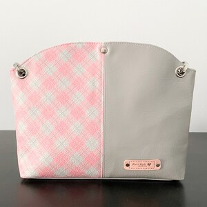 May include: A gray and pink checkered handbag with a silver chain strap and a small leather tag that says "Hand Made with Love".