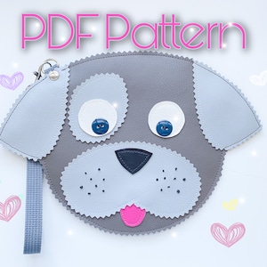 May include: PDF pattern for a gray felt dog-shaped pouch with a pink tongue, black nose, and blue eyes. The pouch has a gray felt strap.