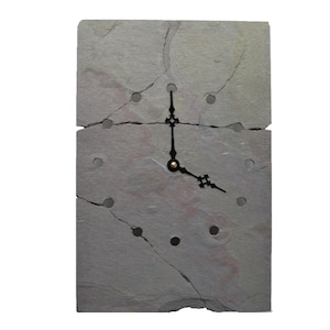 May include: A gray slate clock with black hands and a gold center. The clock face is cracked and has several holes.