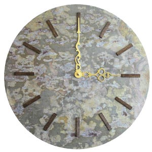 May include: Round wall clock with a textured, mottled gray and tan face. The clock features dark brown wooden markers for the hours and ornate gold-colored hands. The clock's design is simple and modern, suitable for home decor.