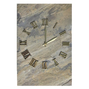 May include: A rustic slate clock with Roman numeral hour markers and gold-colored hands. The clock face is a light brown color with a textured surface.