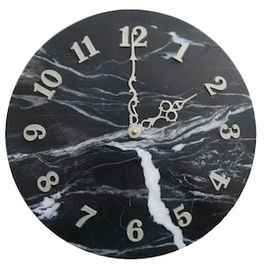 May include: A black and white marble clock face with silver Roman numeral hour markers and silver hands. The clock face is round and has a black marble background with white veins.