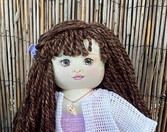 Muñeca coleccionable de 45 cm (18 pulgadas) de color castaño con rostro pintado a mano y vestido de verano color lavanda.