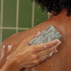 Woman washing her shoulder with an Averal Provence Argan Oil French bar soap in a green tiled shower