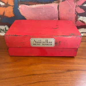May include: Red metal box with a silver label that reads "The American Home Menu Maker".