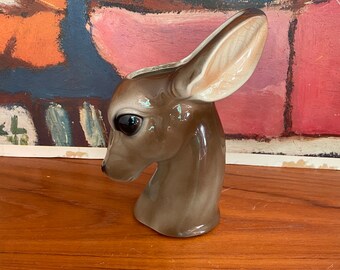 May include: A ceramic fawn head vase with brown and white glaze. The vase is a unique and decorative piece for any home.