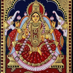 Puede incluir: Una pintura vibrante y detallada de una deidad sentada, adornada con joyas de oro y una prenda roja. Dos elefantes blancos flanquean la figura central, sosteniendo flores de loto. La obra presenta intrincados detalles dorados y un fondo azul oscuro.