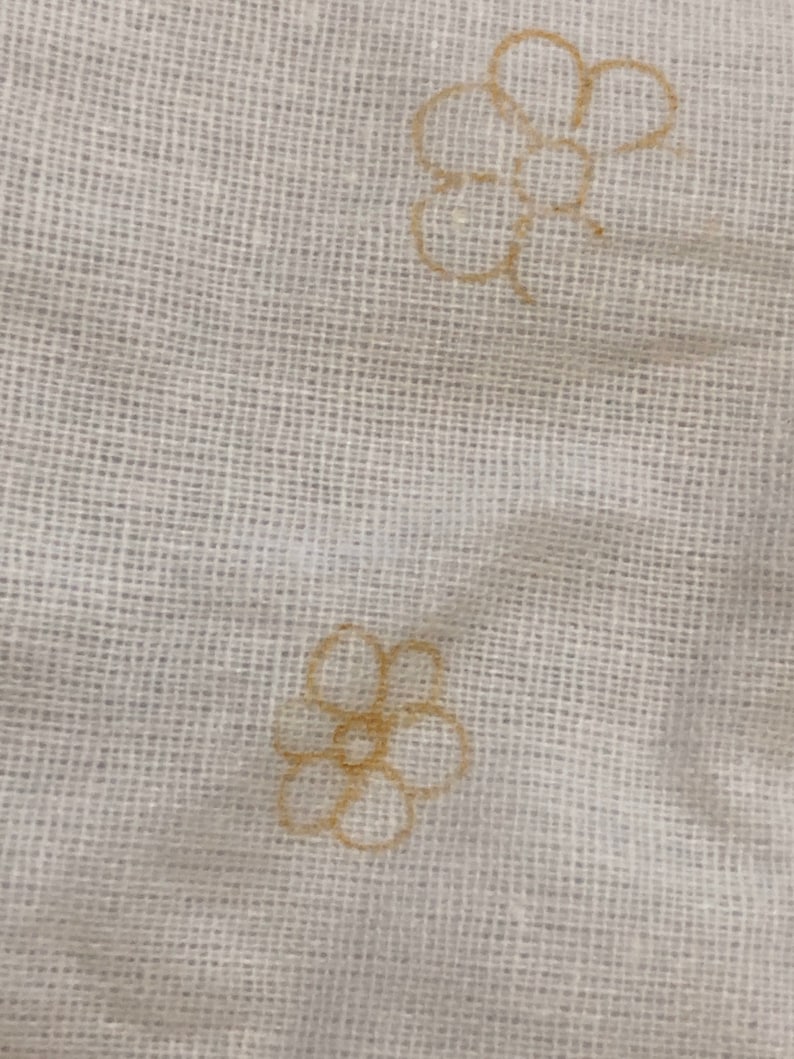 May include: Two brown floral designs on a white fabric background.