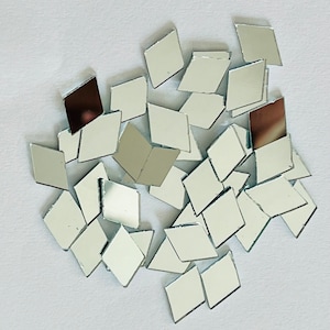 May include: A pile of small, silver, diamond-shaped mirror tiles on a white background.