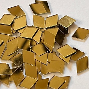 May include: A pile of gold-colored diamond-shaped mirror tiles.