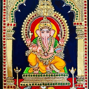 Puede incluir: Una vibrante pintura de la deidad hindú Ganesha, representado con vestimenta amarilla y verde, sentado sobre una plataforma verde. La obra de arte presenta intrincados detalles dorados, un fondo azul oscuro y un borde rojo y dorado. Dos lámparas ornamentadas flanquean la deidad.