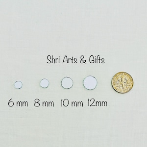 May include: A collection of small, round, mirrored glass pieces, ranging from 6 mm to 12 mm in diameter, are displayed next to a US dime for size comparison. The text "Shri Arts & Gifts" is above the glass pieces.