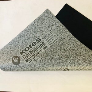 May include: A gray and black sheet of Kores Carboplane Super 503 paper. The paper is textured and has the words "Kores Carboplane Super 503" printed on it. The paper is non-curling, non-smudging, light fast, and long lasting.