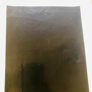 May include: A black, textured, rectangular sheet of paper.