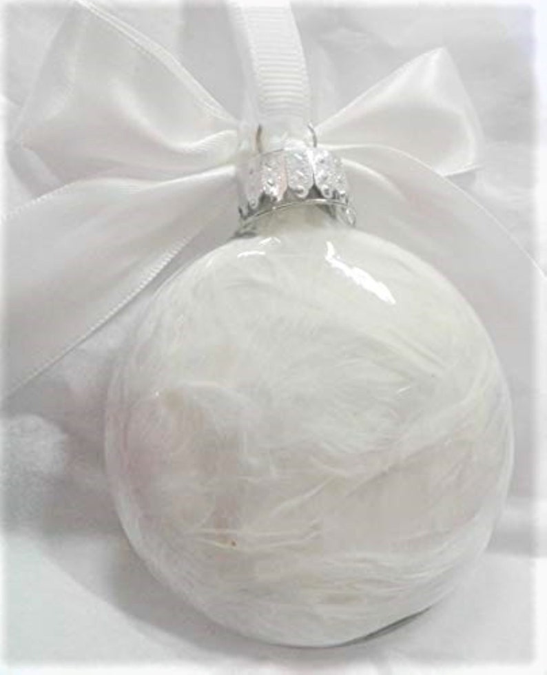 May include: White glass Christmas ornament with a white satin ribbon and bow. The ornament has a textured, feathery design.