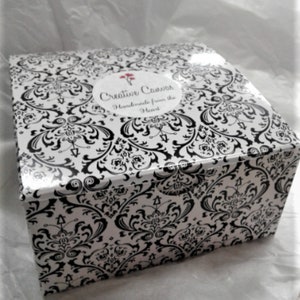 May include: A black and white damask patterned box with a white label that says "Creative Canvas Handmade from the Heart".
