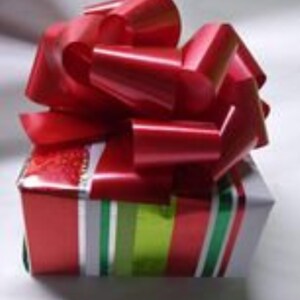 K&ouml;nnte beinhalten: Eine rot-gr&uuml;ne gestreifte Geschenkbox mit einer gro&szlig;en roten Schleife aus Satin oben drauf.
