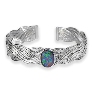 May include: A silver braided cuff bracelet with a large oval opal gemstone in the center. The opal has a dark blue, green, and red iridescent sheen.