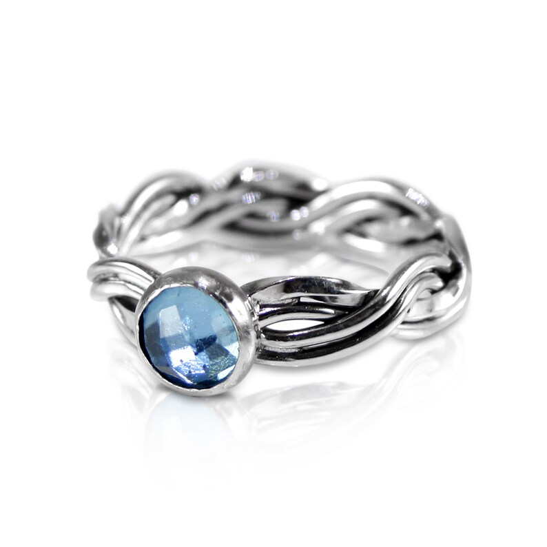 May include: A silver ring with a braided band and a light blue gemstone.